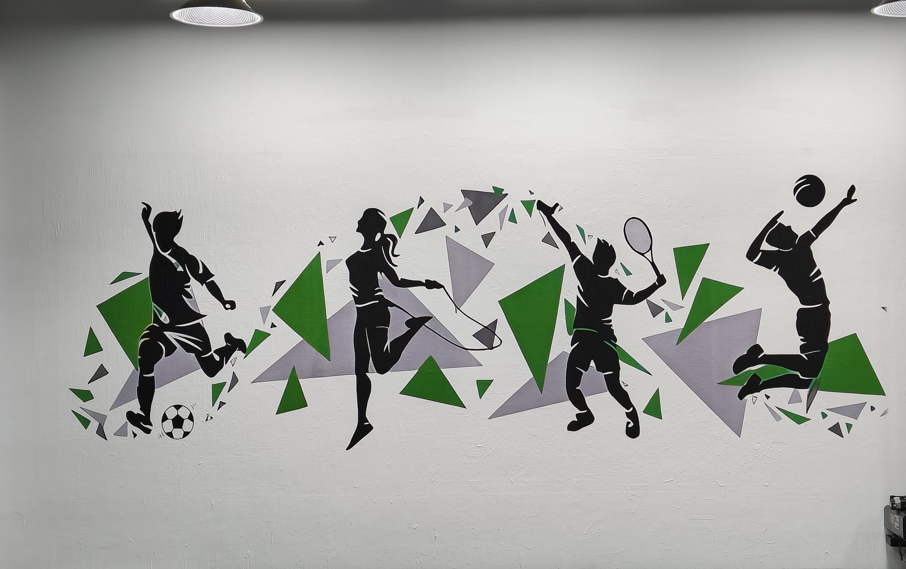 Silhouetted footballer, tennis player and basketball players in green and grey across a wall